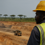 A high-resolution photograph of an African open-pit mine with industrial machinery and processing facilities under a wide sky.